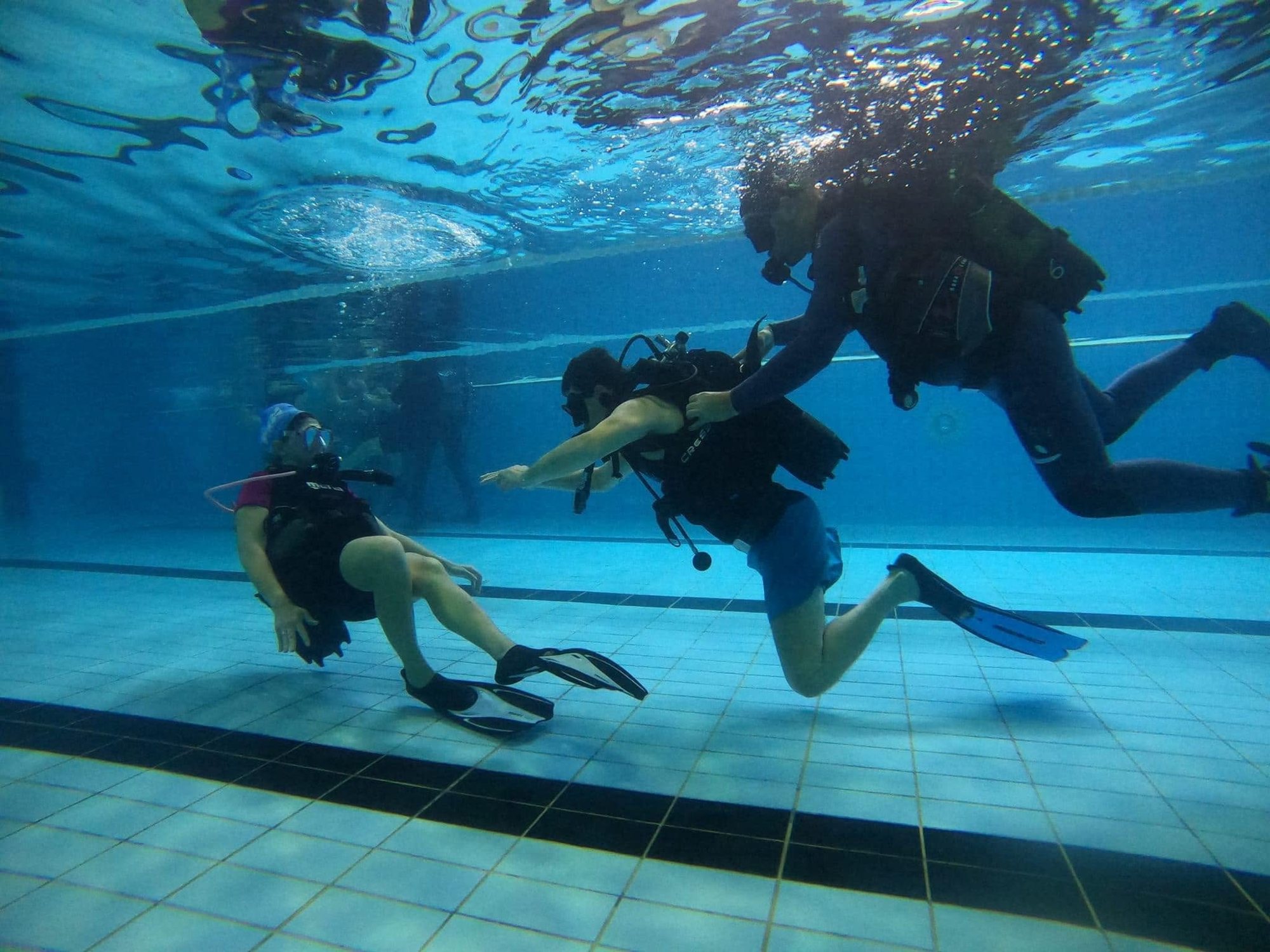 Lezione di immersione subacquea in piscina con istruttore e allievi